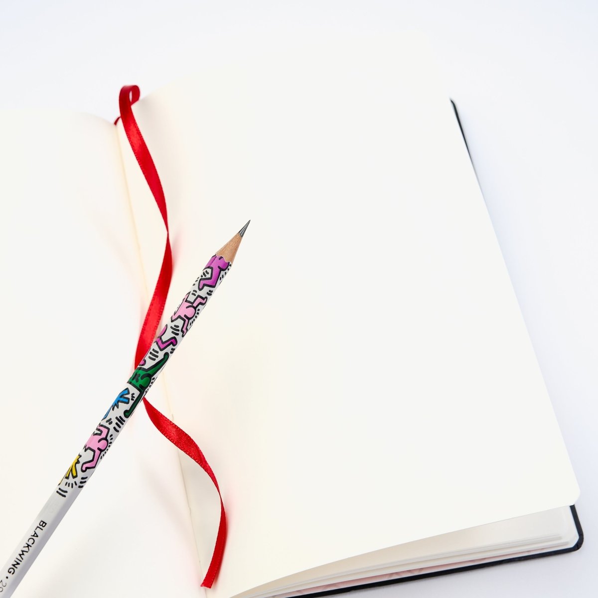 Open notebook with a colorful pencil on a white background.