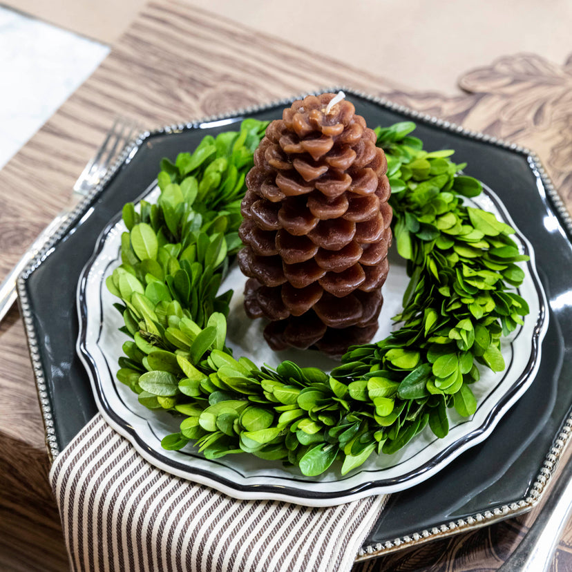 Mill's Floral mini boxwood wreath on a table setting with a brown pinecone shaped candle inside. 
