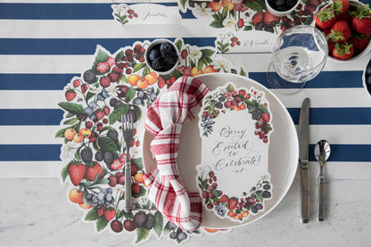 A Die-cut Berry Wreath Placemat by Hester &amp; Cook with a paper napkin on top, creating a delightful tablescape.