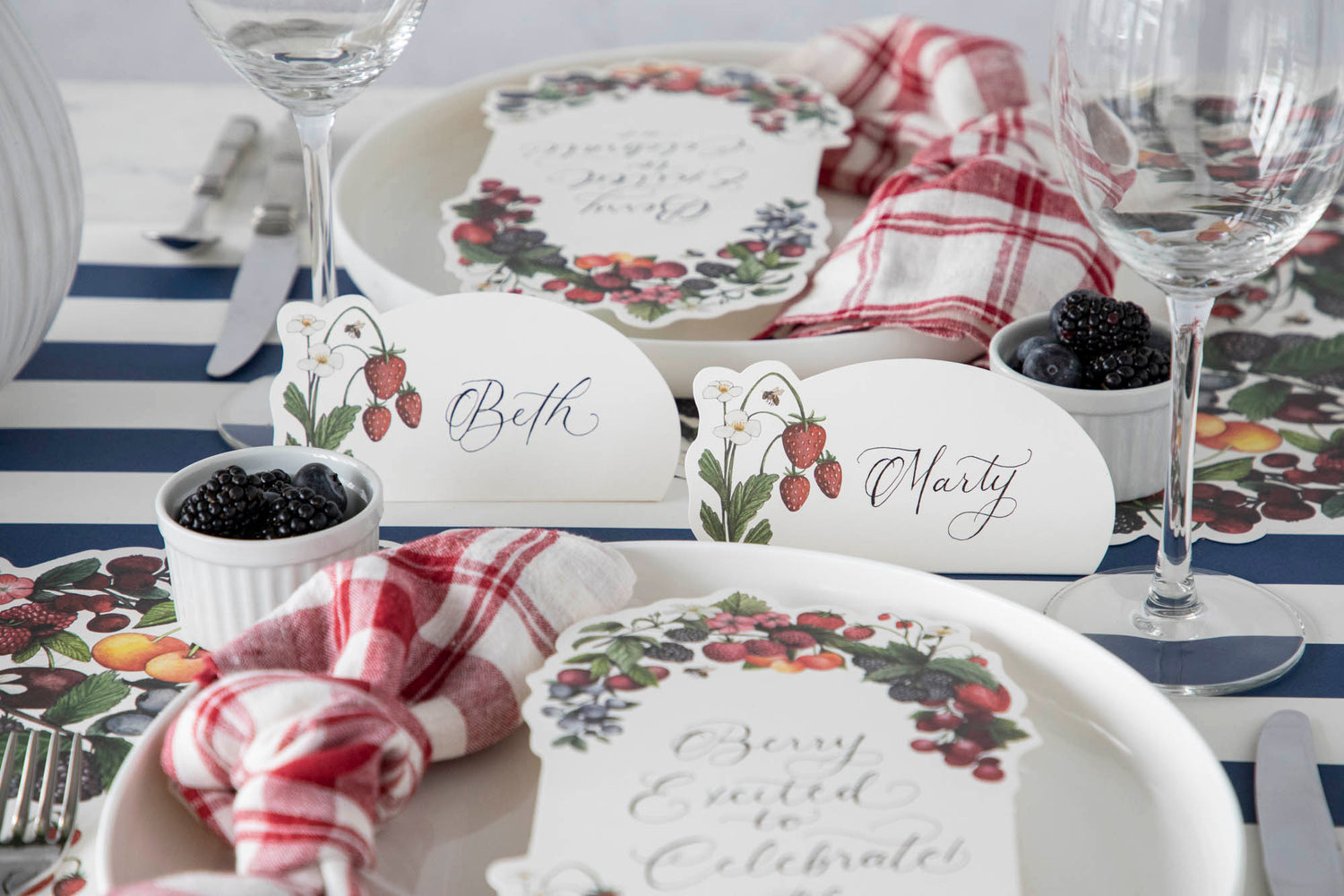 A table adorned with plates and glasses, featuring summer strawberries and an elegant touch from Hester &amp; Cook&