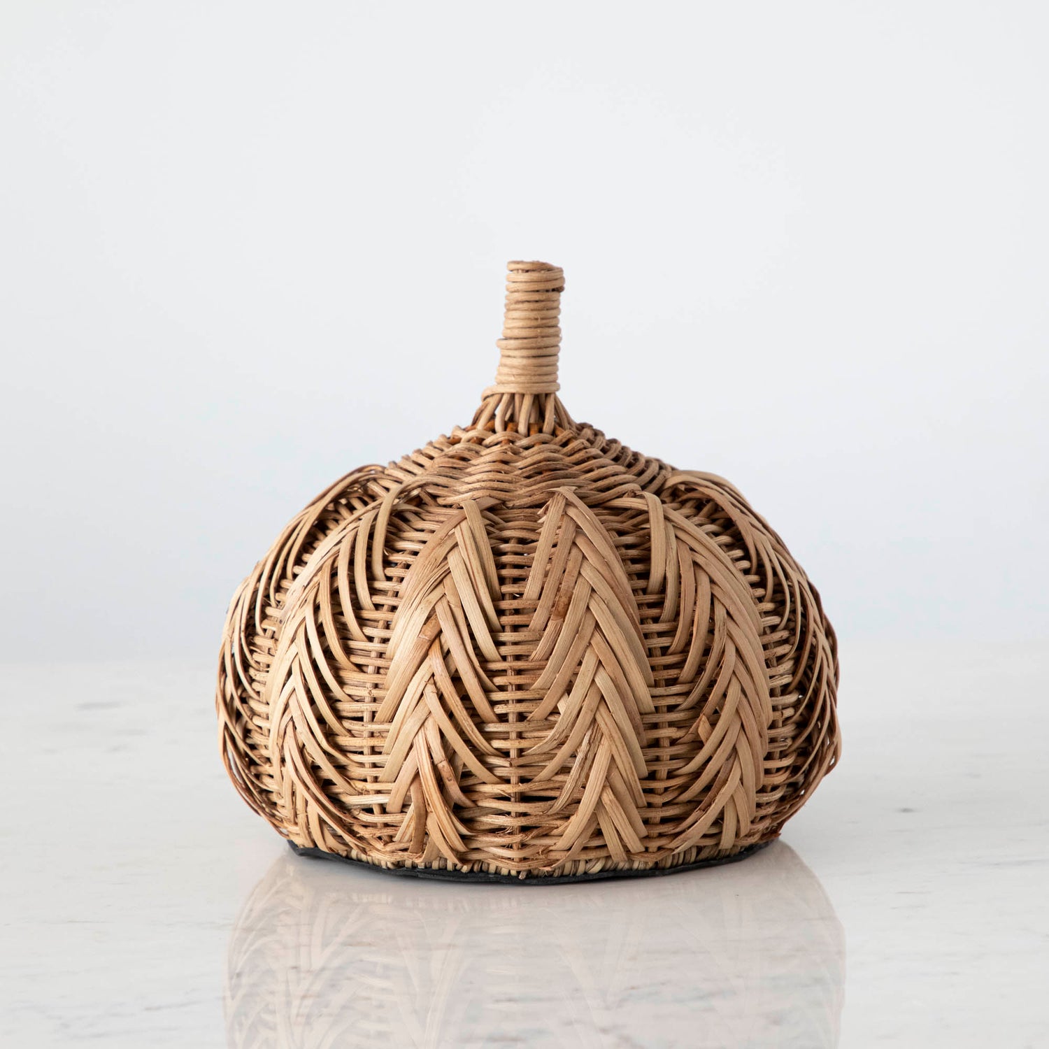 A medium woven pumpkin on marble.