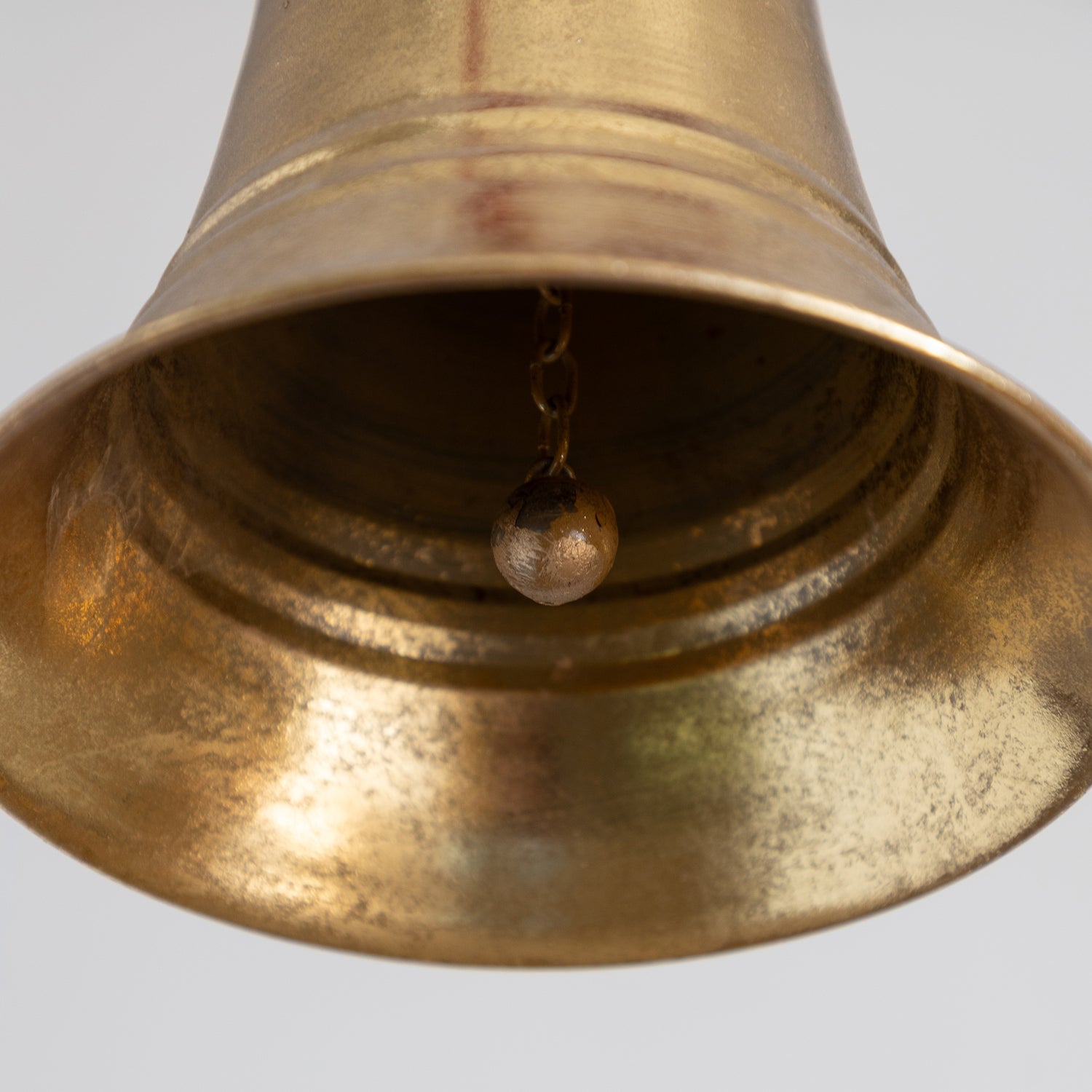 Close-up of a brass bell on a light gray background