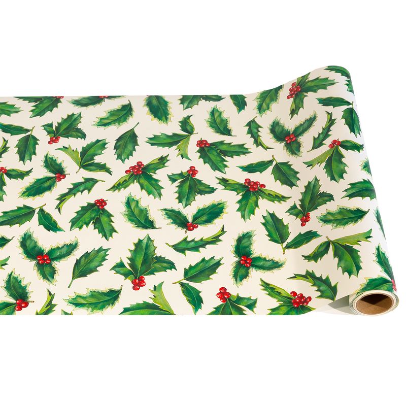 Roll of Christmas-themed runner paper with holly leaves and berries on a white background