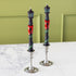 Two Lamppost Taper Candles with a green wreath wrapped around the post, red bows and glittery panes in silver candle holders.