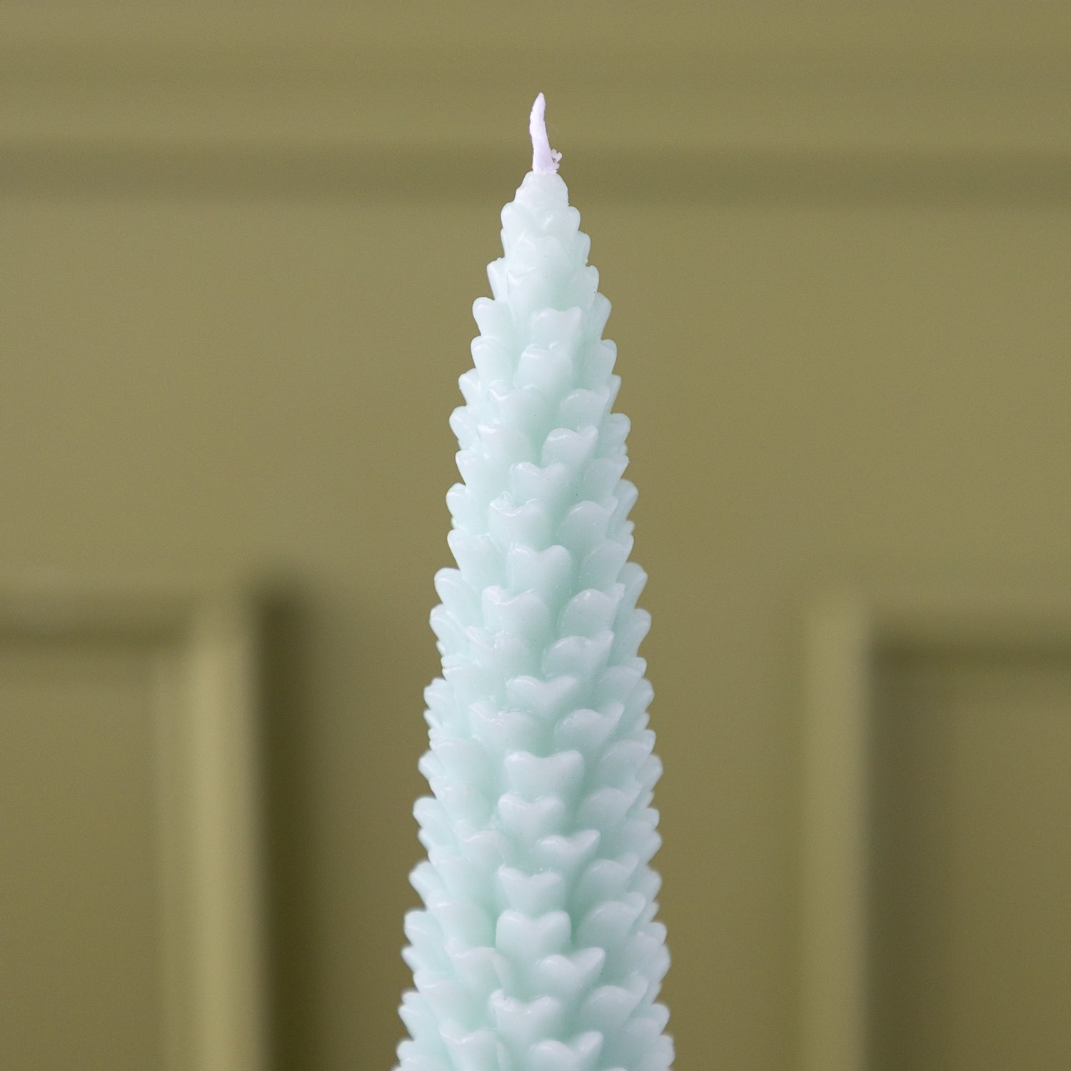 A close up of the Mint Large Pinecone Taper Candle.