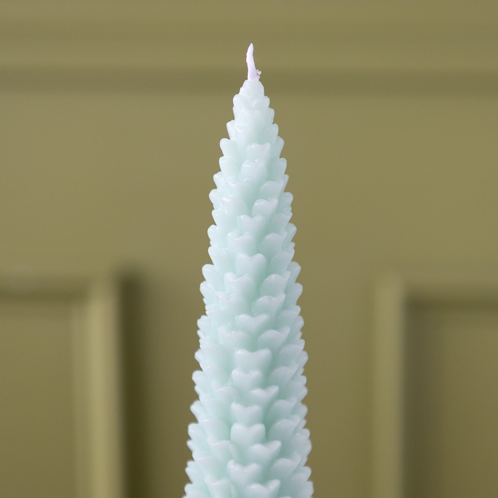 A close up of the Mint Large Pinecone Taper Candle.
