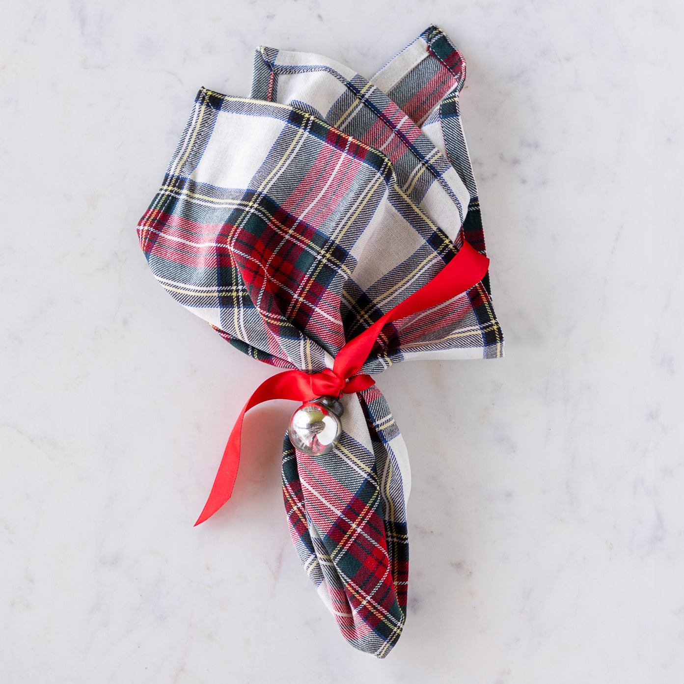 Plaid napkin tied with a red ribbon and Silver Ball Mercury Glass Ornament.