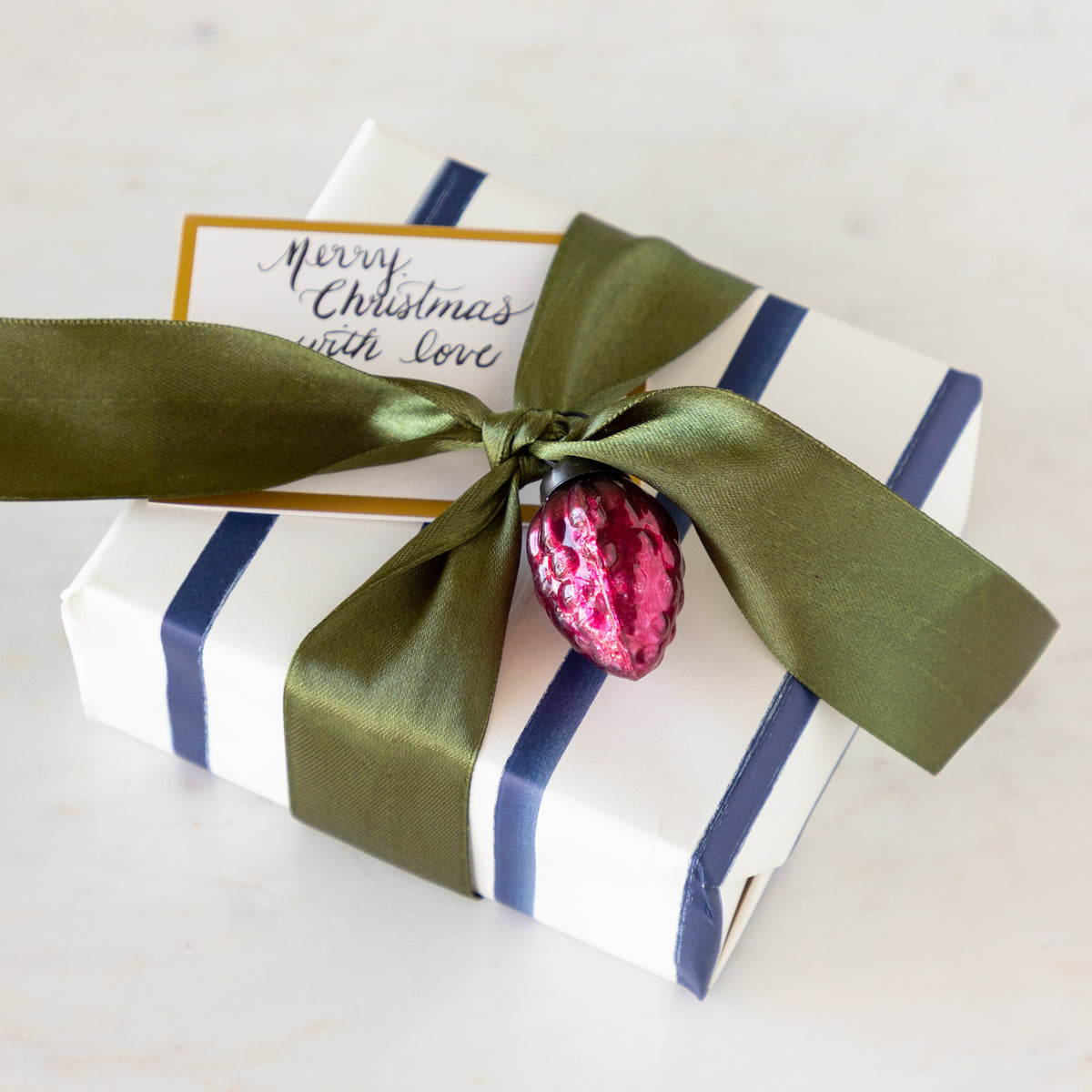 Gift box tied with green ribbon and a Multi Color Mercury Glass Ornament.