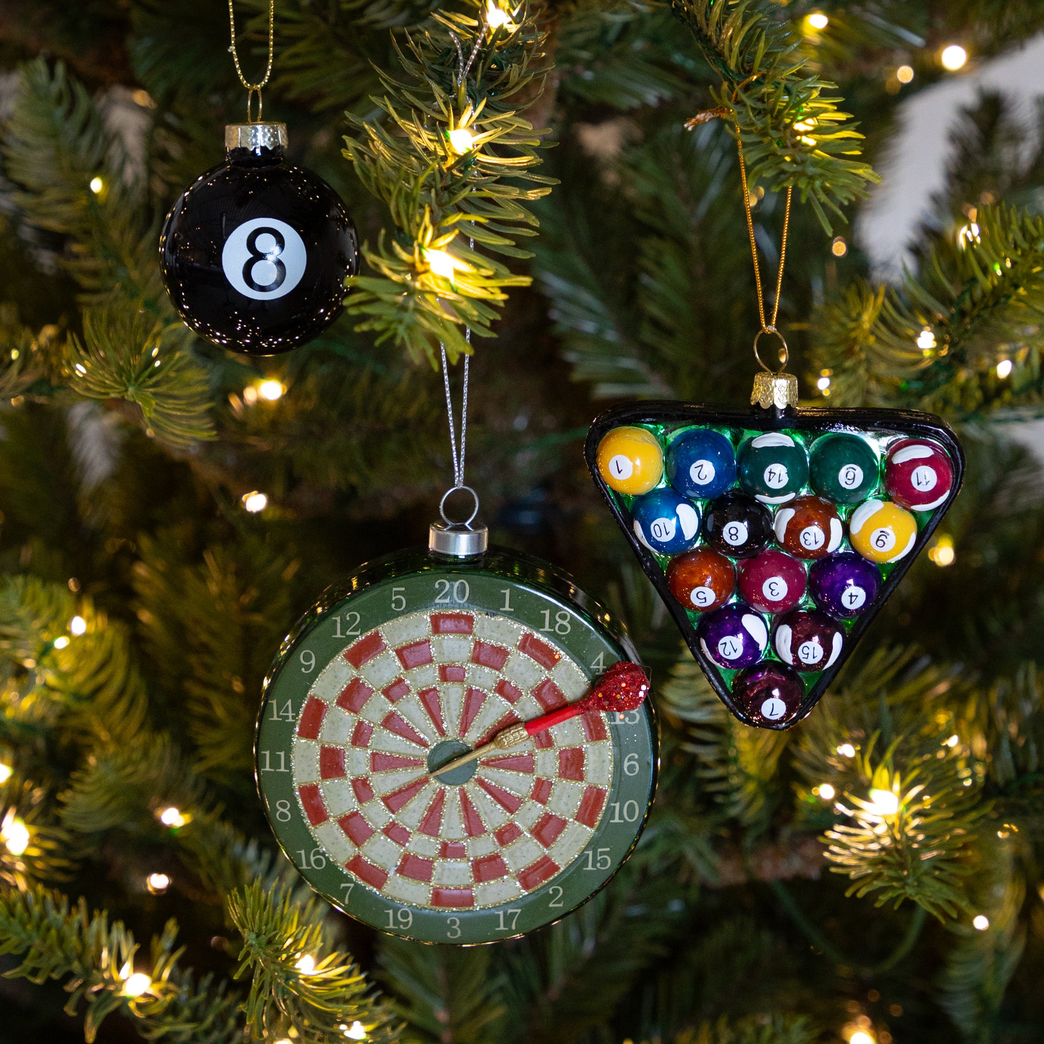 Decorative Christmas ornaments shaped like a dartboard and pool ball triangle on a tree.