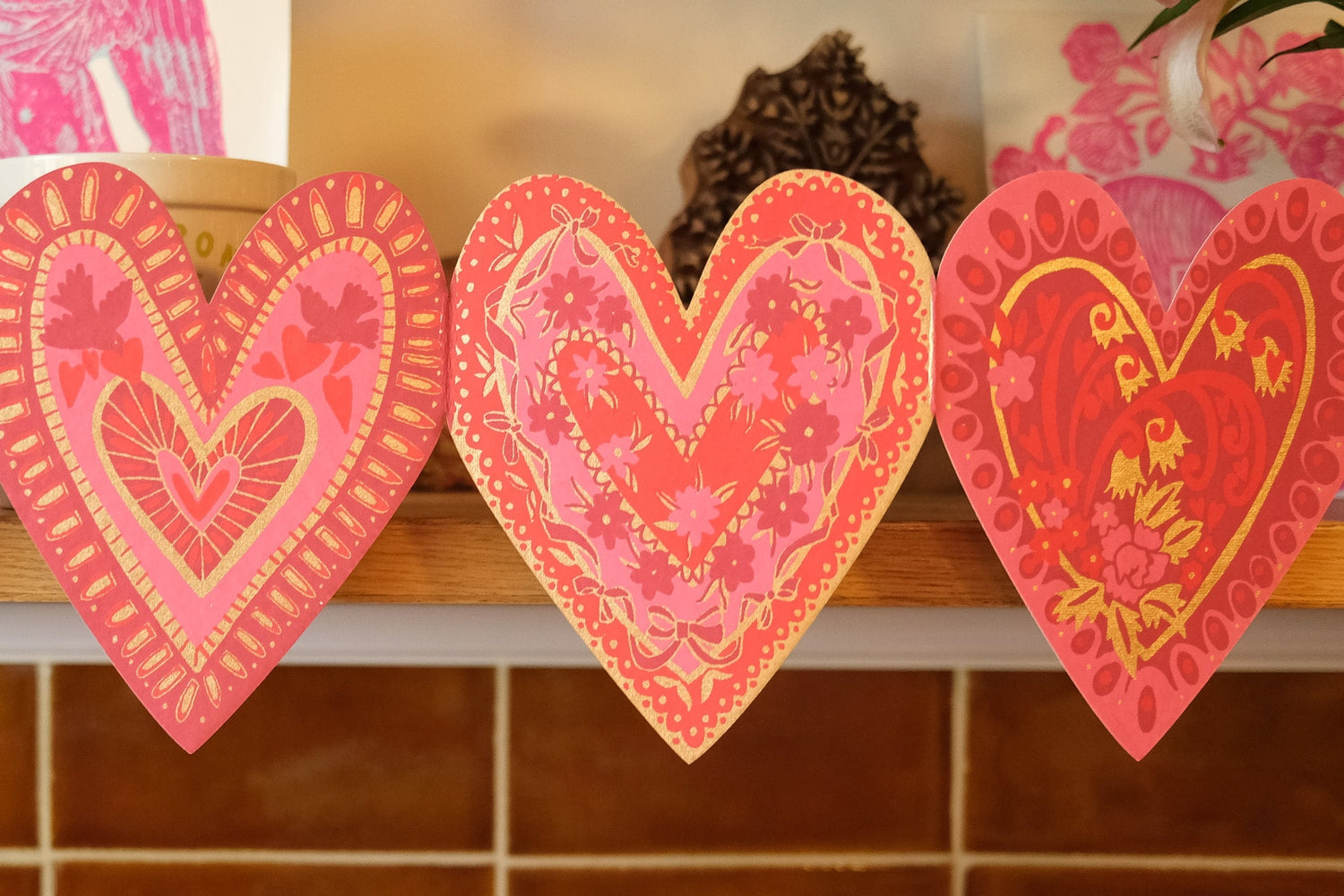 Three heart-shaped decorative garland with floral patterns on a shelf.