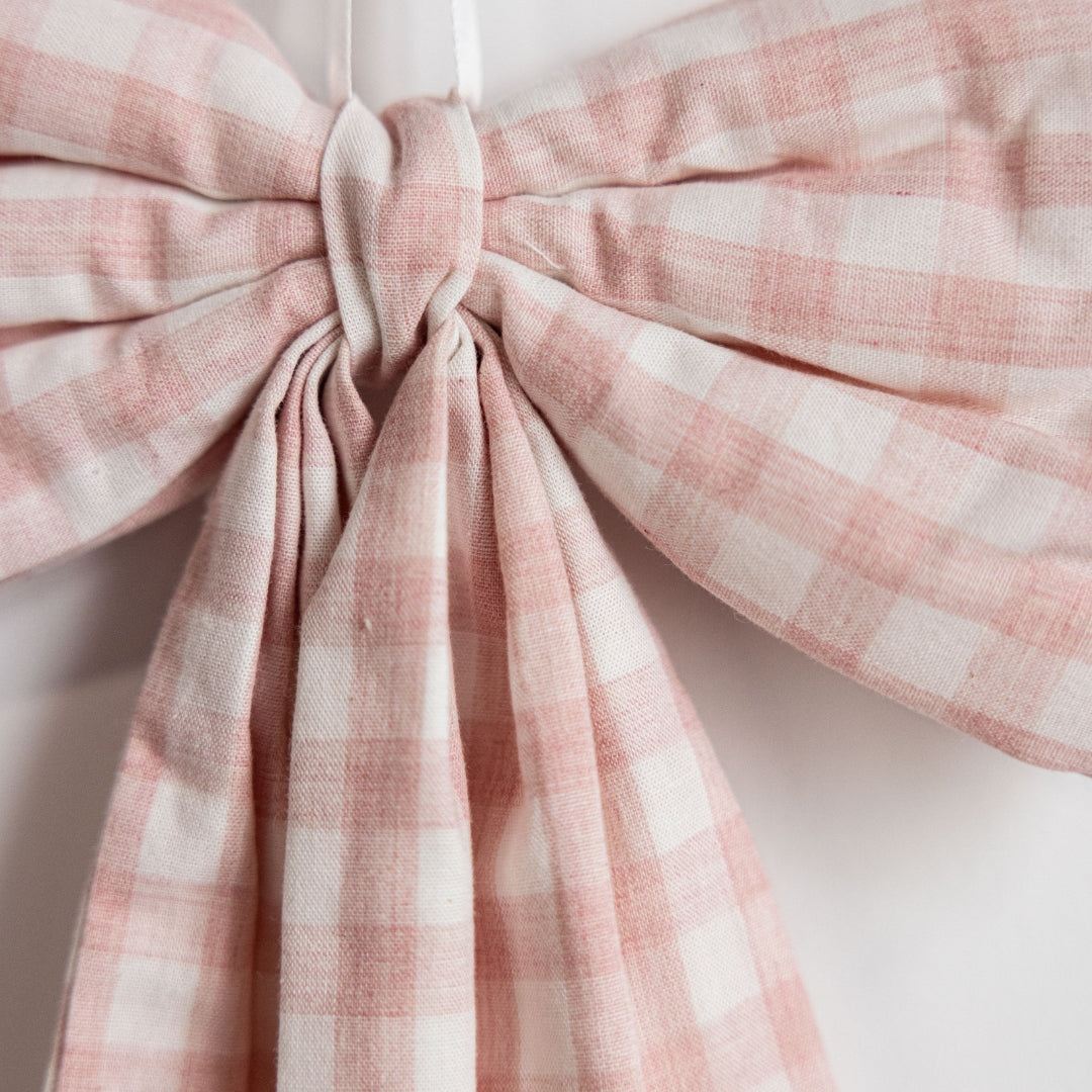 Close-up of a pink and white checkered bow on a white background