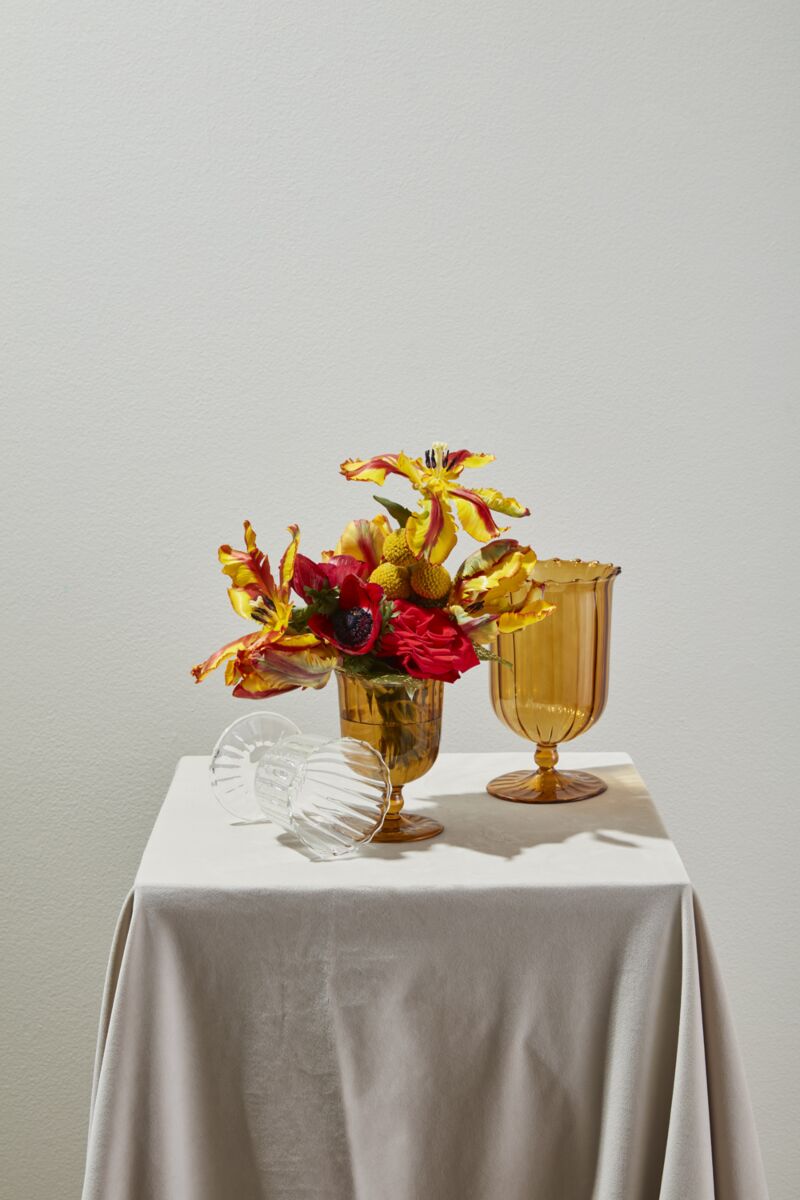 Decorative glassware with flowers on a white tablecloth against a plain background
