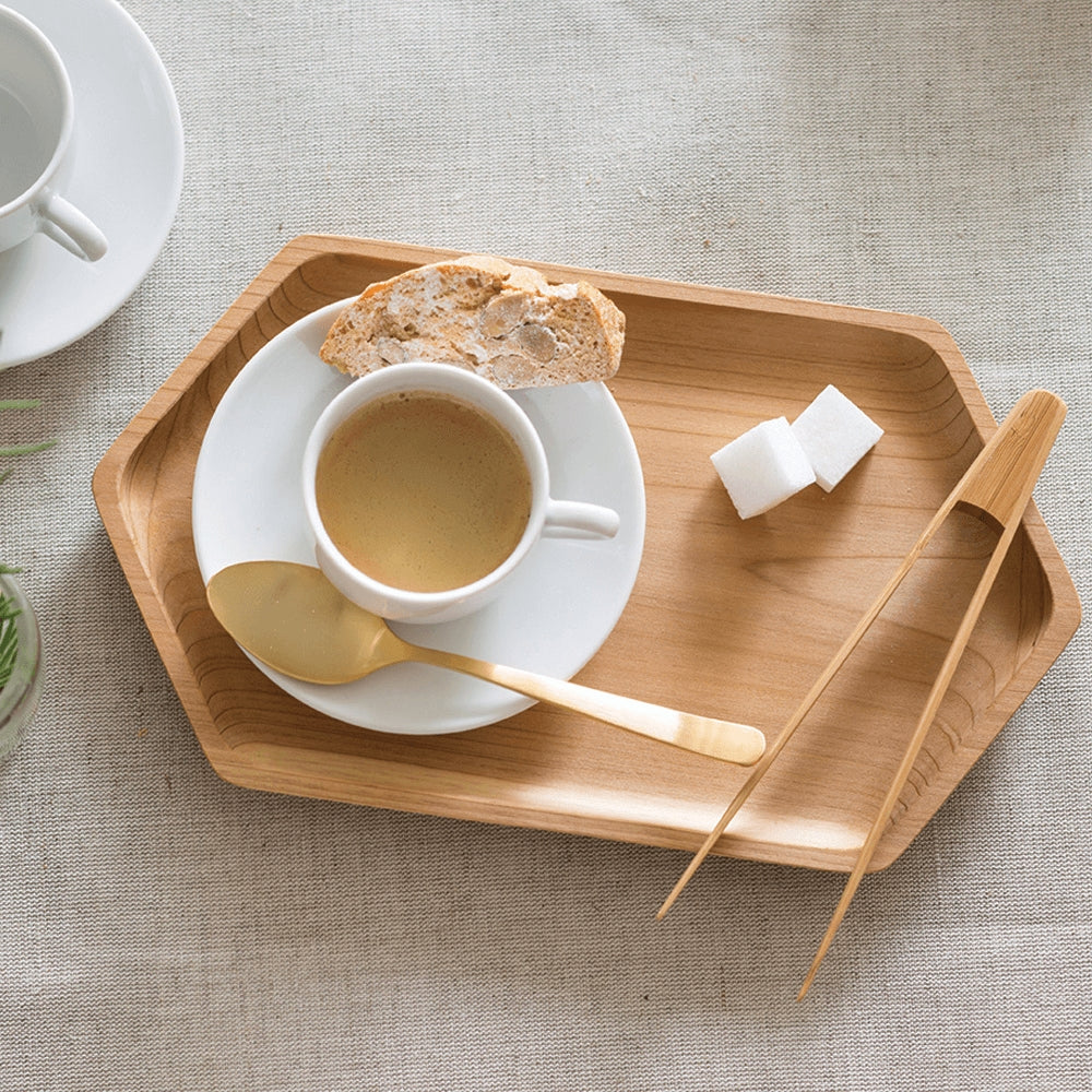 Cup of coffee with a biscotti on a wooden tray with a gold spoon