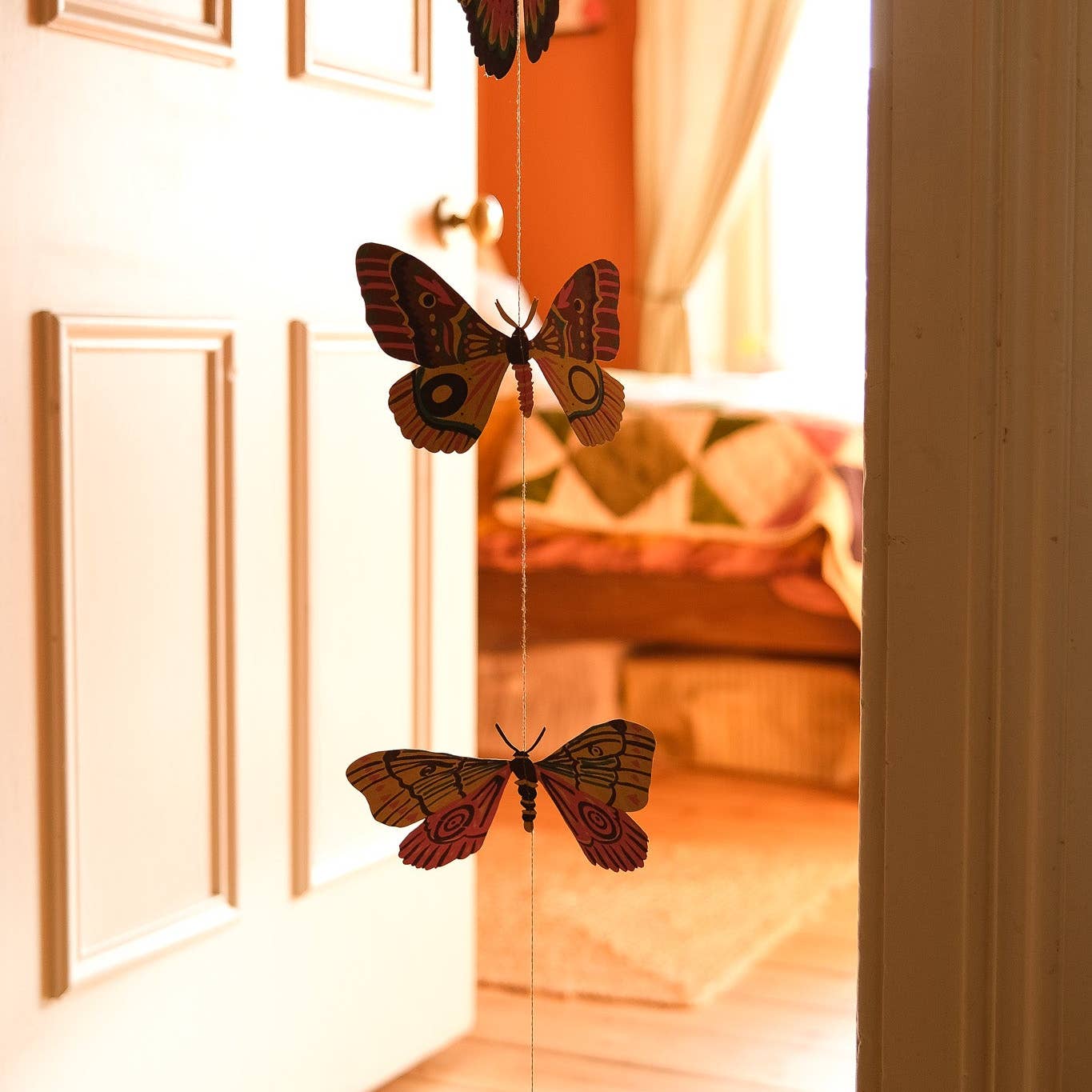 Decorative butterflies hanging on a string in front of a door.