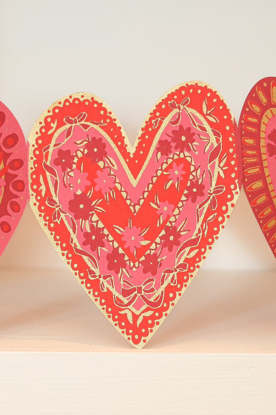 Decorative heart-shaped garland with floral patterns on a beige background.