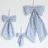 Three blue and white gingham bow decorations of different sizes hanging on a plain white wall.