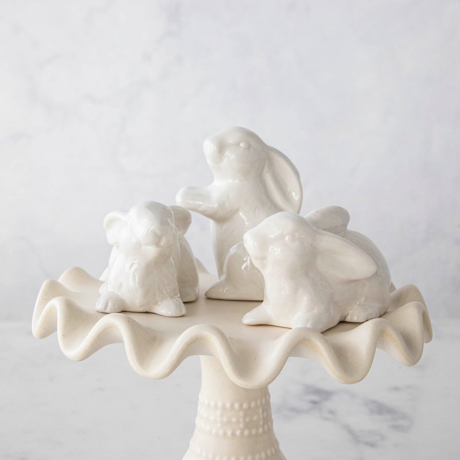 A group of Creative Co-Op Ceramic Bunnies, Set of 6, on a cake stand.