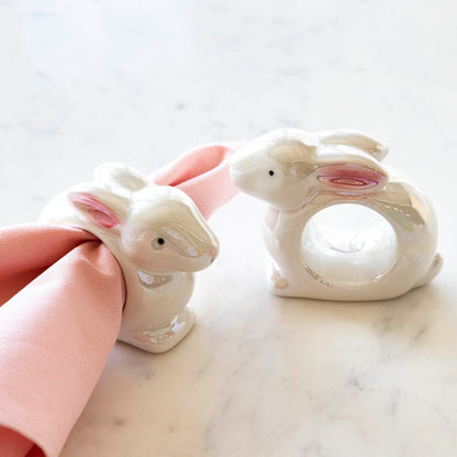 Two Glitterville Bunny Napkin Rings with a springy touch on a napkin.