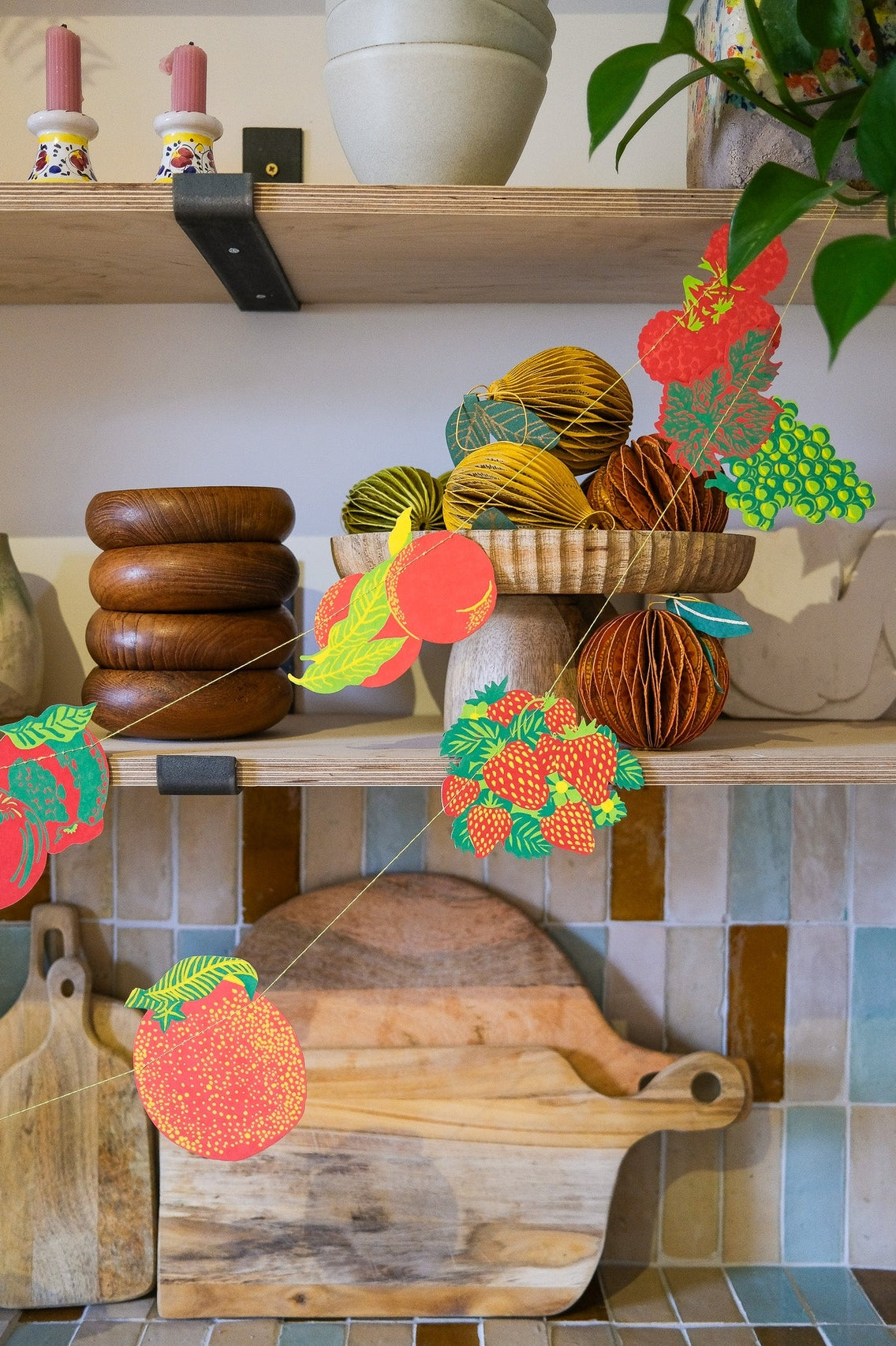Kitchen shelf with wooden bowls, a cutting board, and decorative elements on a tiled wall.