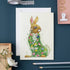 Greeting card with a rabbit illustration on a blue surface with stationery items.