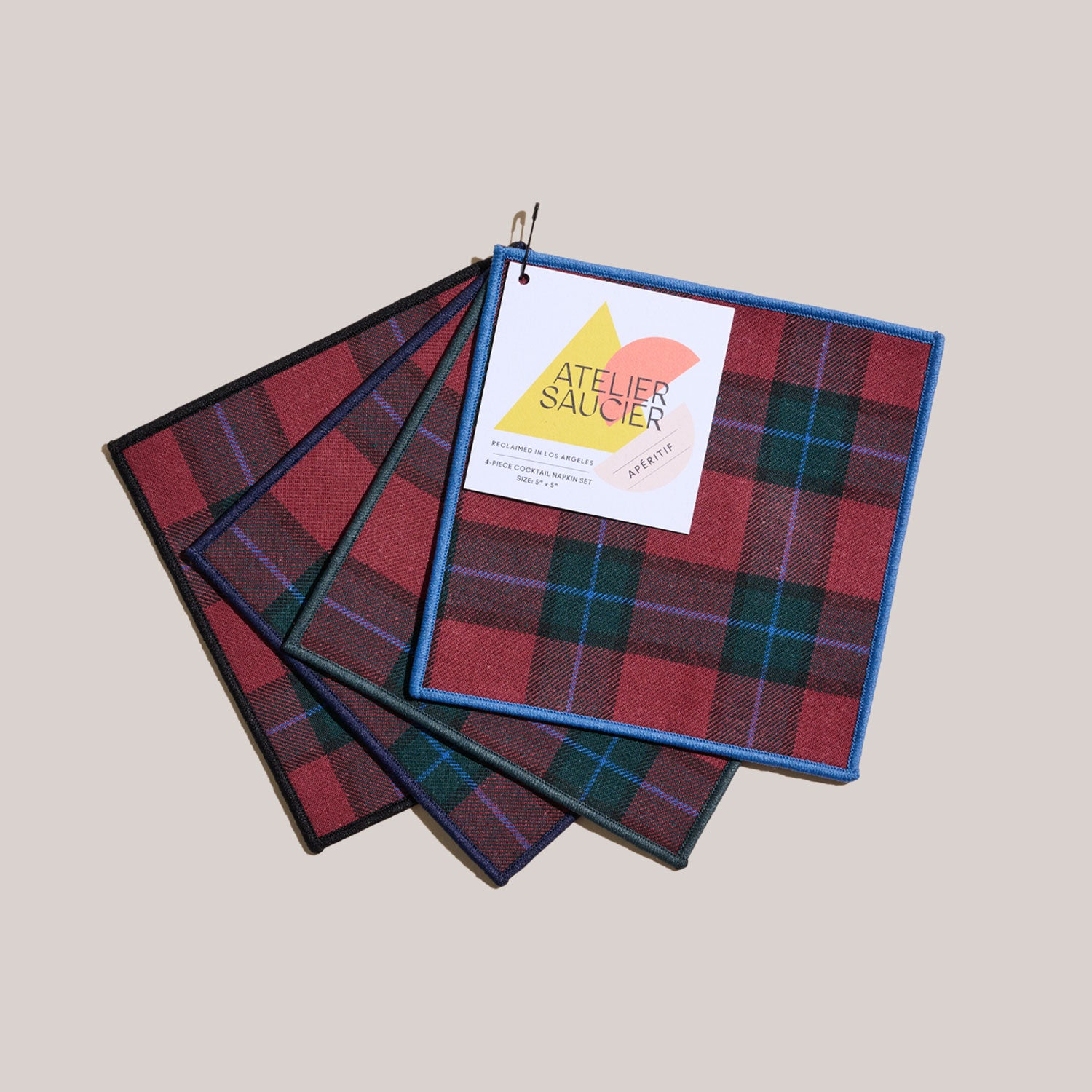 A set of four plaid cocktail napkins with a label indicating the brand &