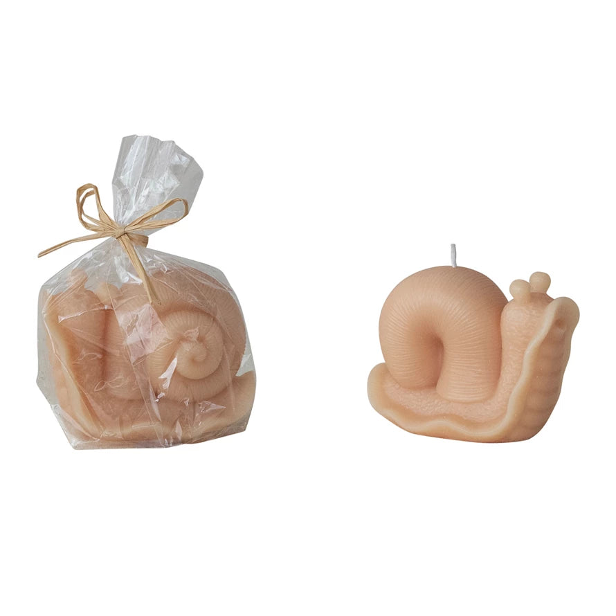 Snail-shaped candle next to a snail-shaped candle in packaging on a white background