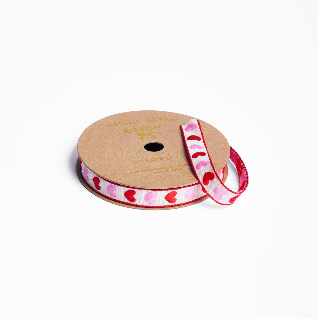 Spool of ribbon with heart pattern on a white background.