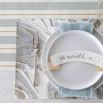 An elegant place setting with a Hester &amp; Cook Slate &amp; Gold Awning Stripe Runner, plate, silverware, and napkin perfect for entertaining.