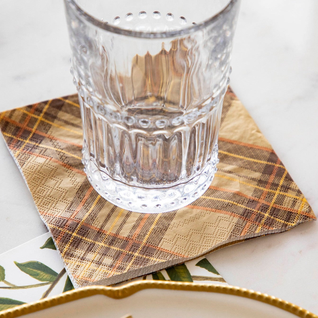 A glass of wine on a Autumn Plaid Napkin by Hester &amp; Cook on a table.