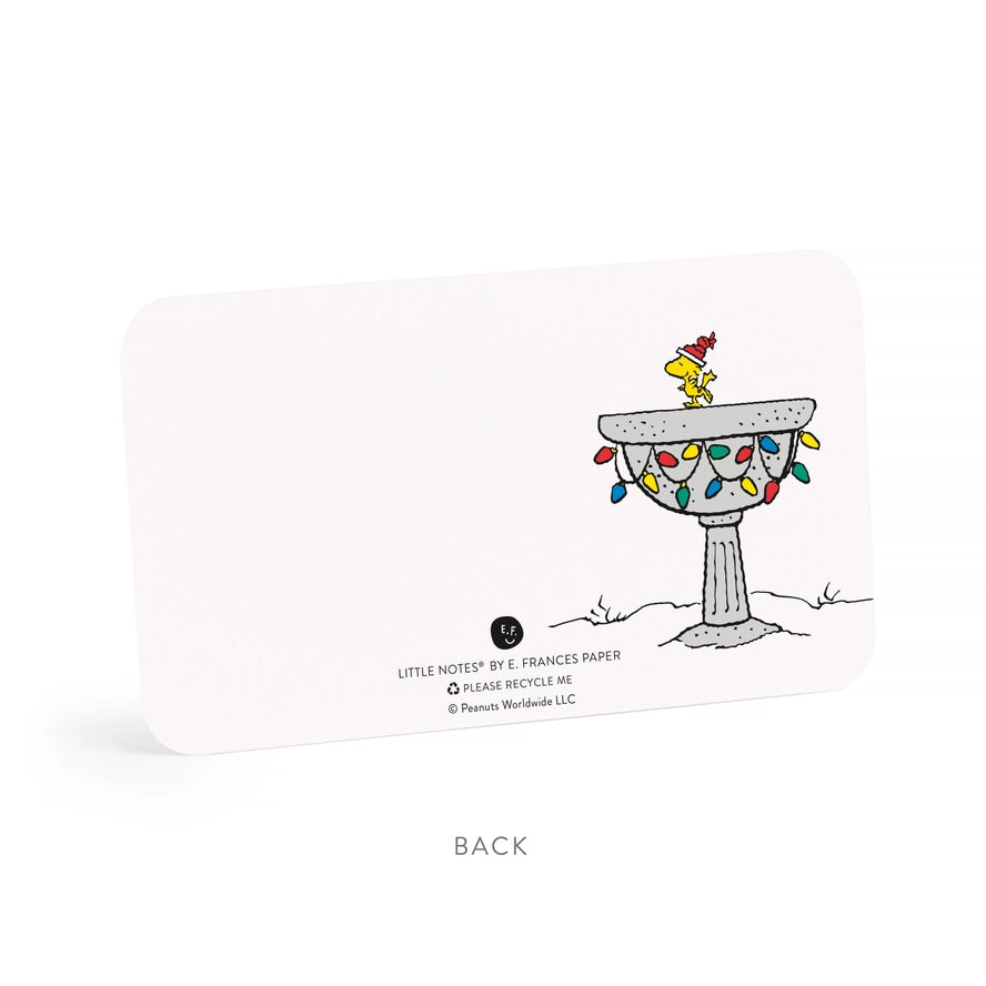 A white rectangular card or packaging piece shown on a clean white background, with a small illustrated scene on the right side featuring a yellow bird perched on a pedestal decorated with multicolored Christmas lights. Text at the bottom reads BACK.