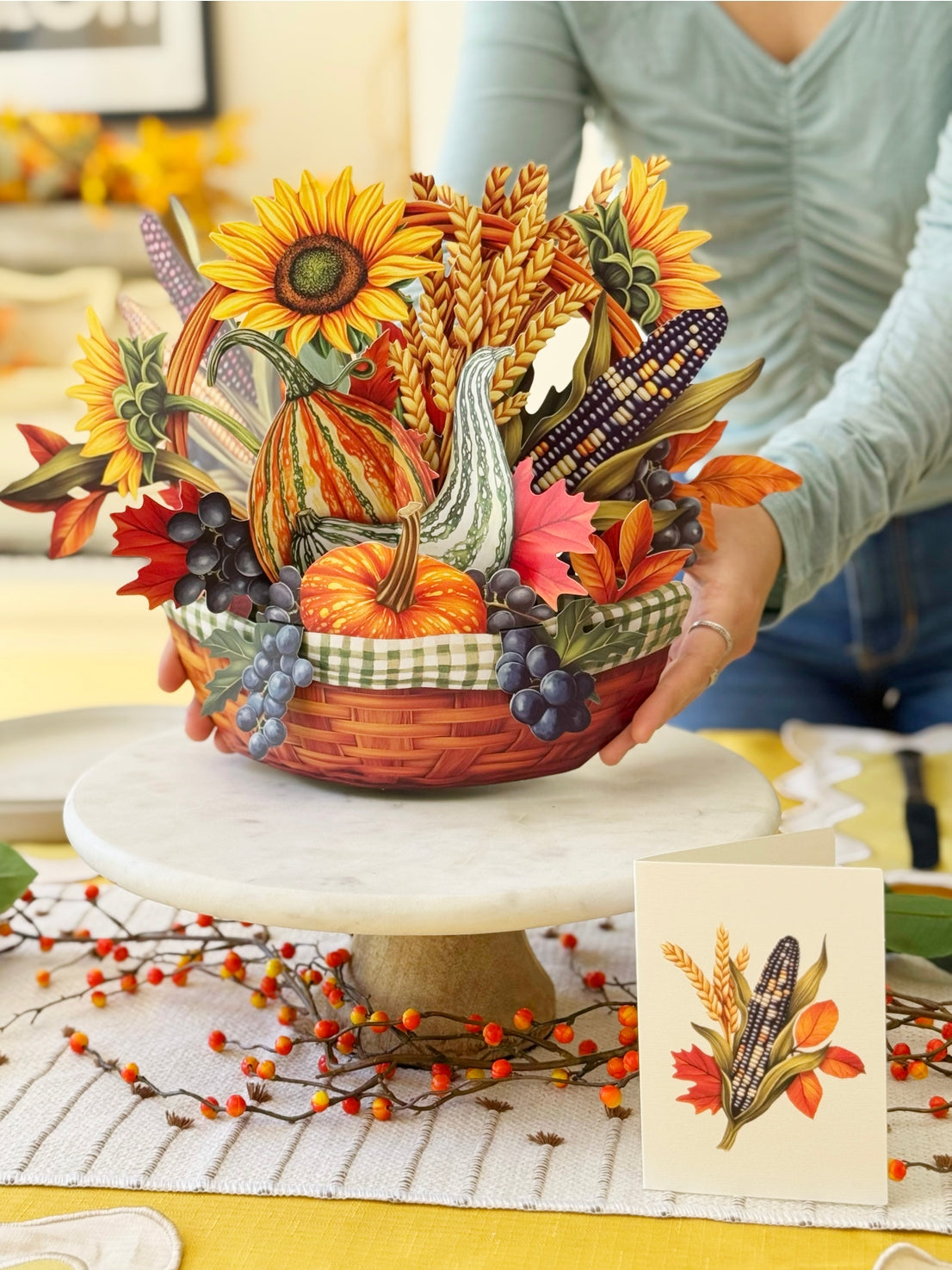 Paper decorative Thanksgiving basket with cornucopia, pumpkins, and sunflowers on a table.