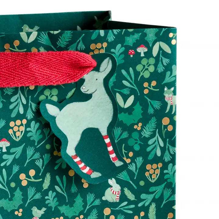 Gift bag with a deer design and red pull tab on a green patterned background
