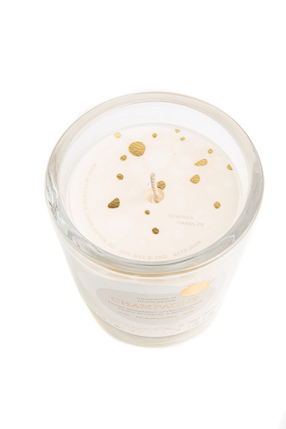 Candle in a glass jar with gold specks on a white background.