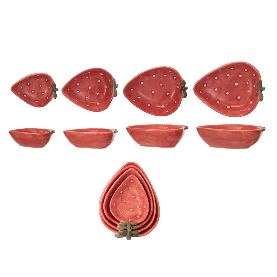Set of strawberry-shaped ceramic measuring cups on a white background.