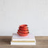 Set of red strawberry shaped measuring cups stacked on a stack of books with a white background.