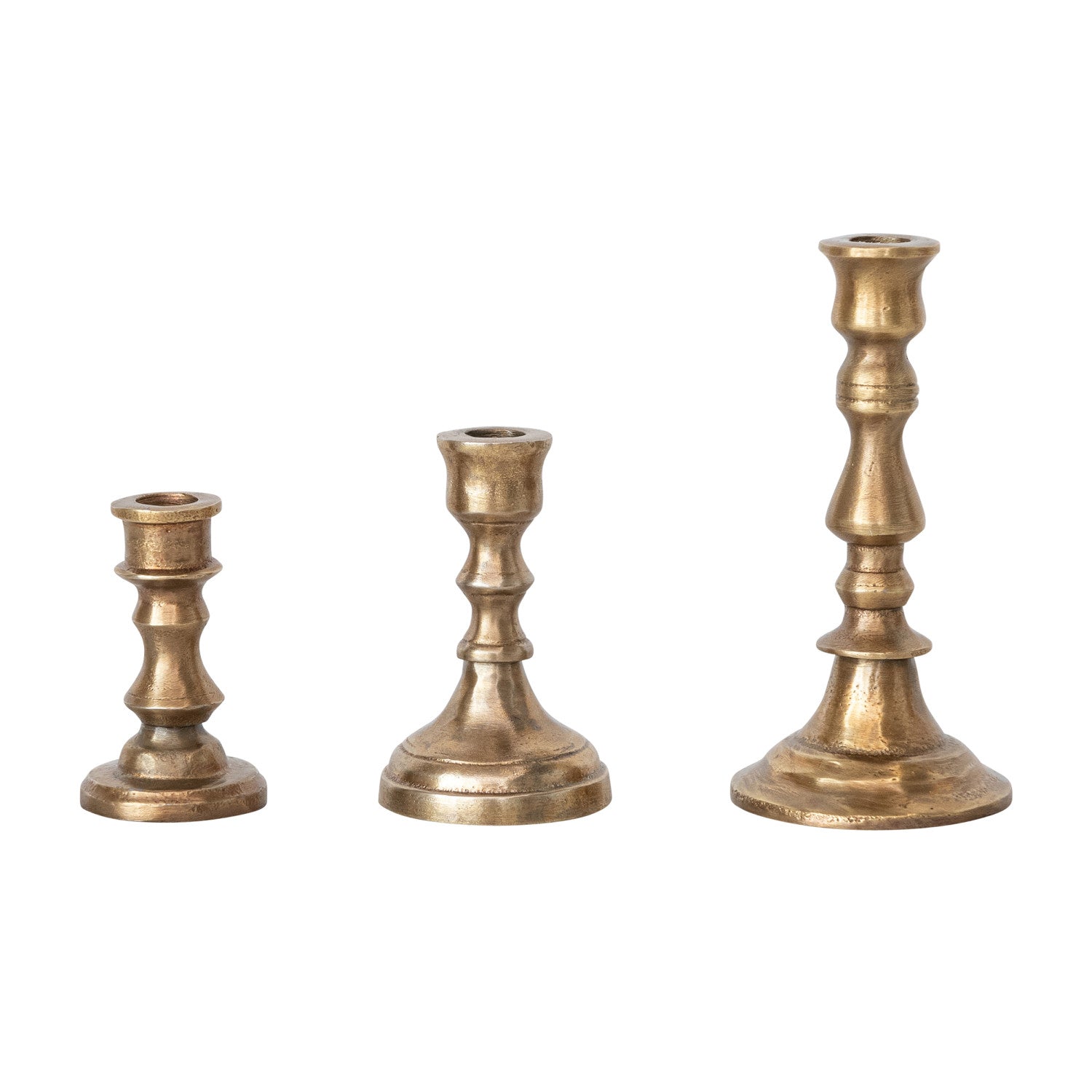 Three brass candle holders of different heights on a white background.