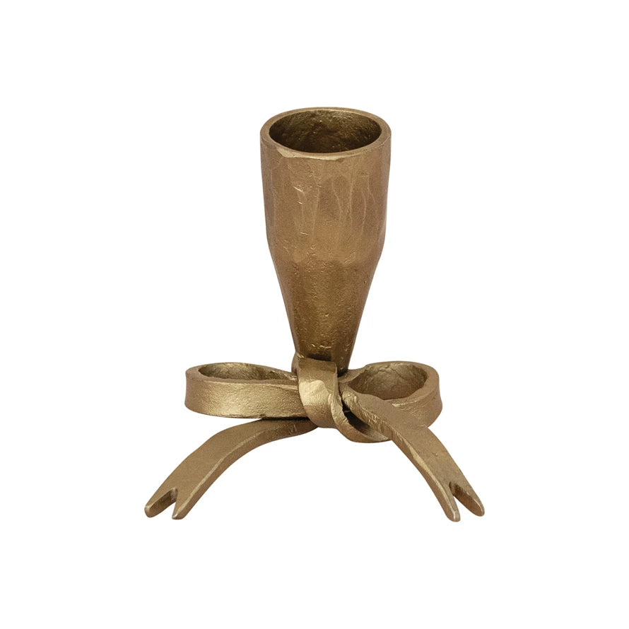 Brass taper candle holder with bow detail at the bottom on a white background.