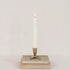 Candle in a decorative holder on top of stacked books against a plain background.