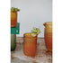 Set of textured glass tumblers with a drink and garnish on a wooden surface.