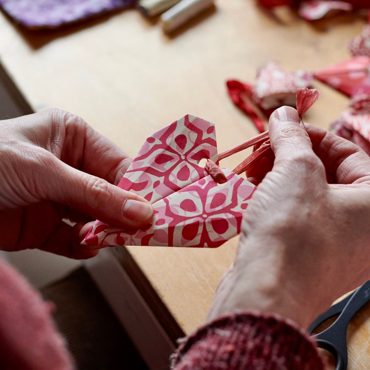 Red and pink origami hearts being crafted. 