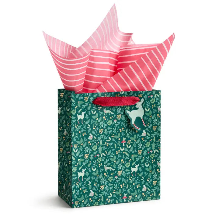 Gift bag with deer pattern and pink tissue paper on a white background
