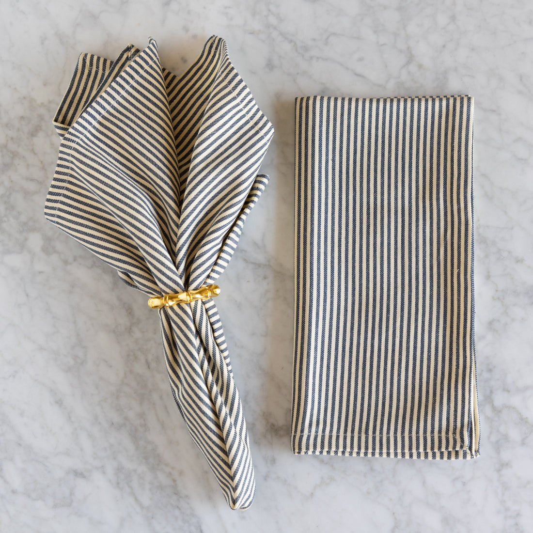 Striped napkin with a gold ring on a marble surface.