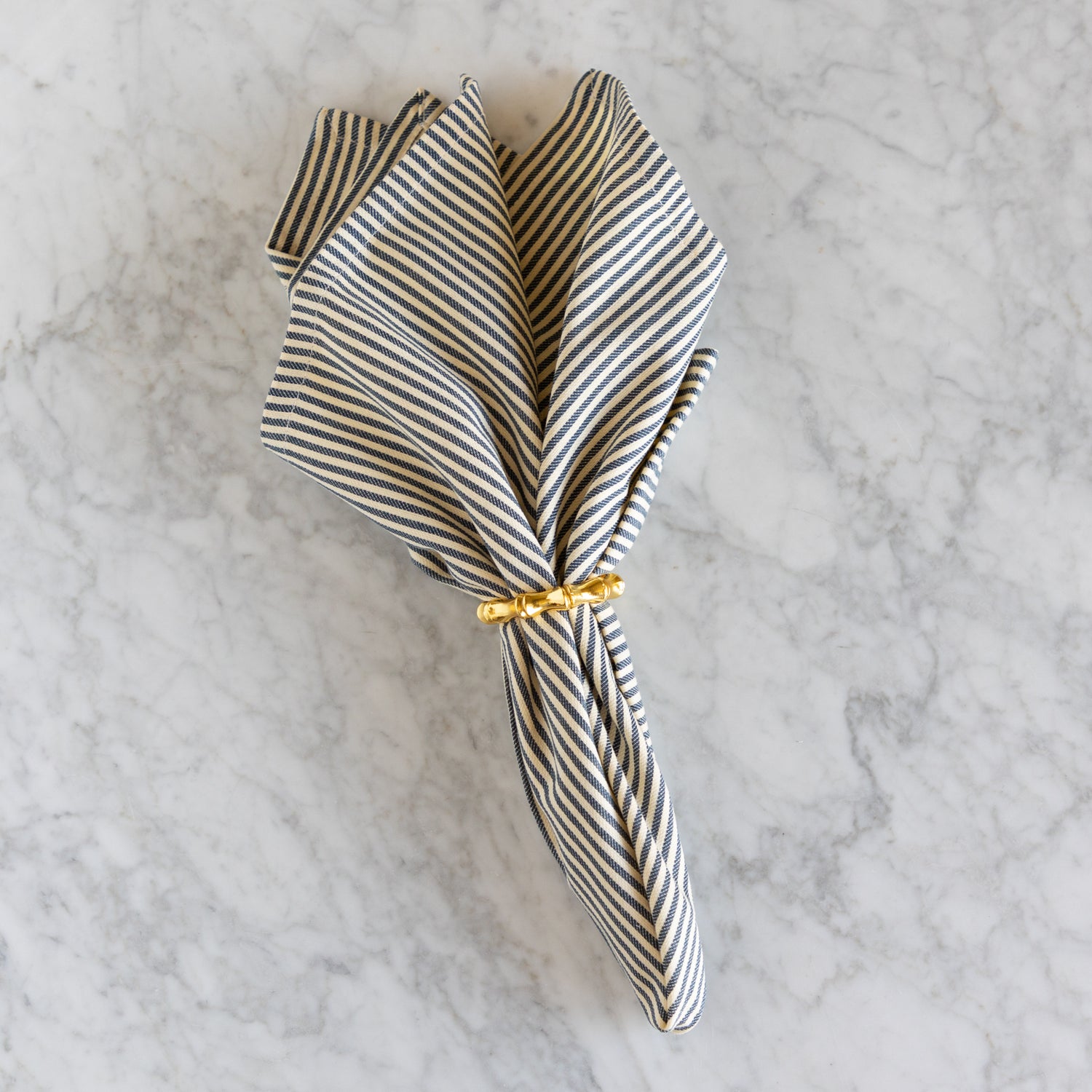 Striped napkin with a gold tie on a marble surface.