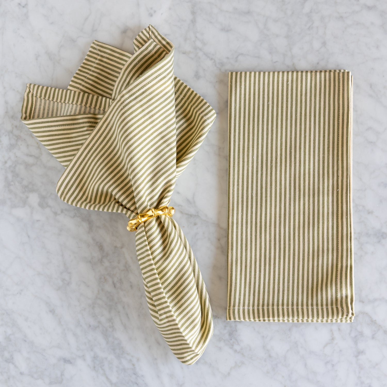 Striped napkin with a gold ring on a marble surface.