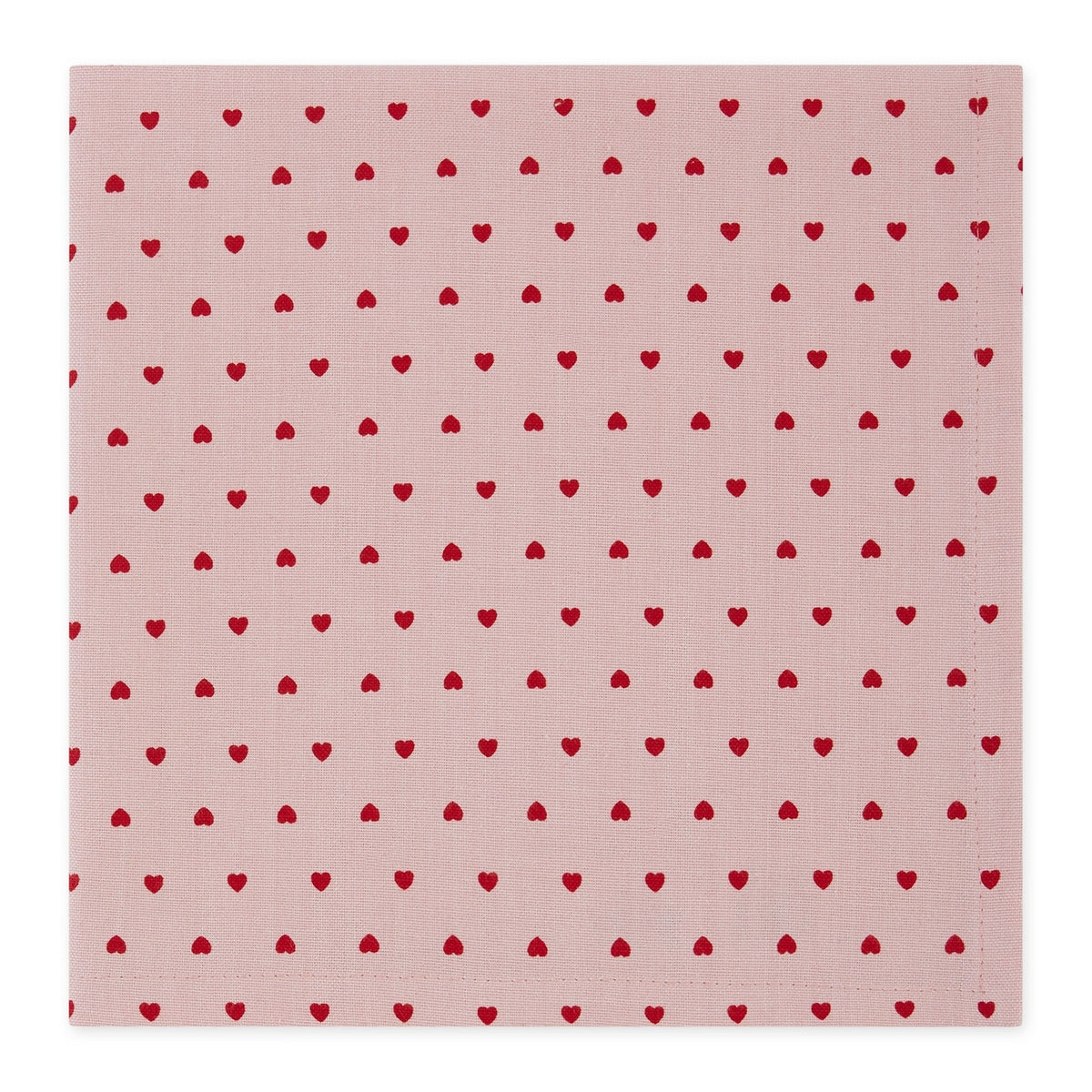 A square pink fabric napkin with a repeating pattern of small red hearts, shown flat against a white background.