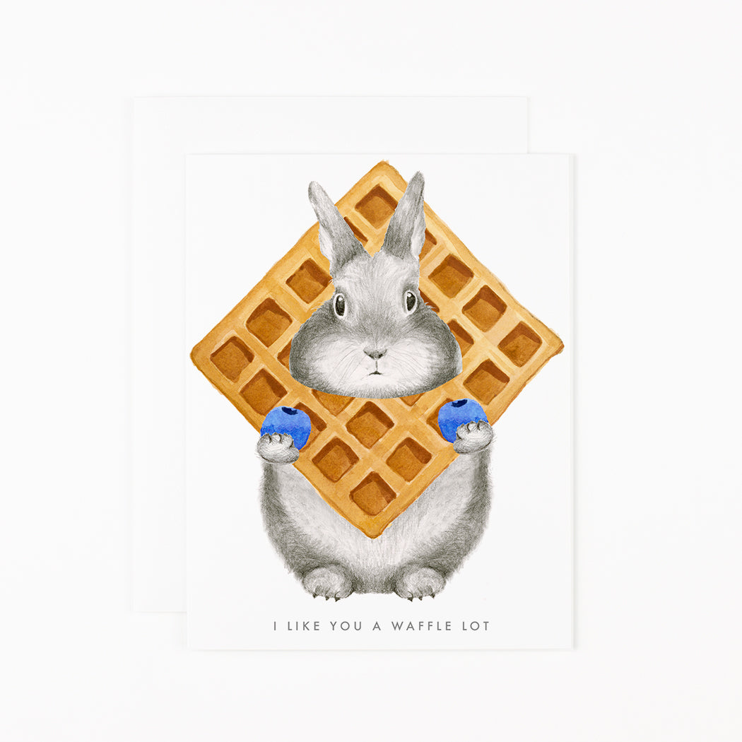Greeting card with hand-drawn graphite bunny Hancock peaking through a waffle holding a blueberry in each hand.  Text reads &quot;A like You a Waffle lot&quot;