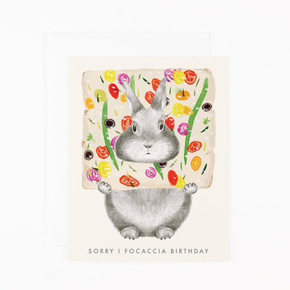 Dear Hancock greeting card with a hand-drawn graphite bunny peeking through focaccia bread with text that reads &quot;Sorry I focaccia birthday&quot;.