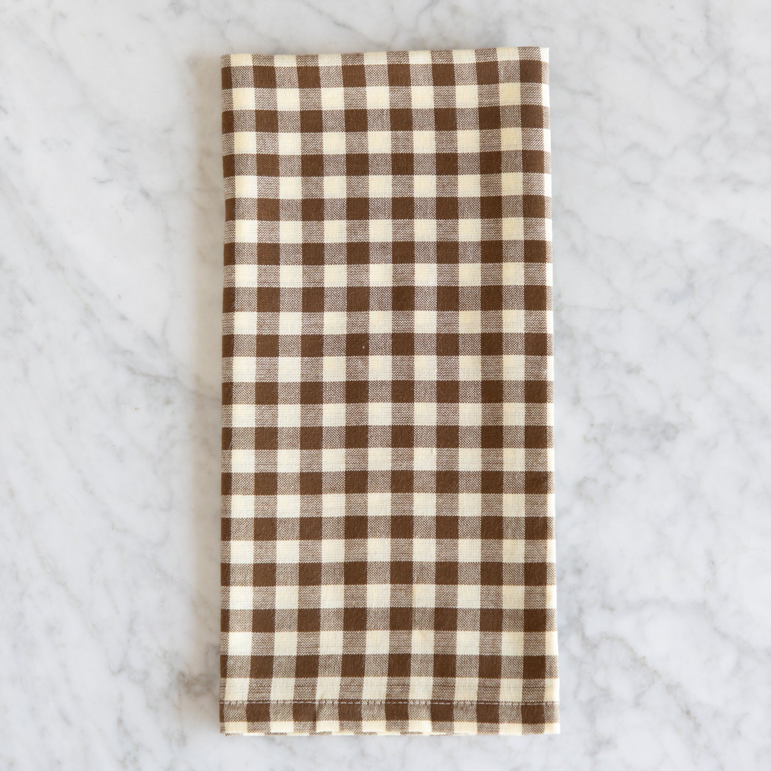 Brown and white checkered napkin on a marble surface.
