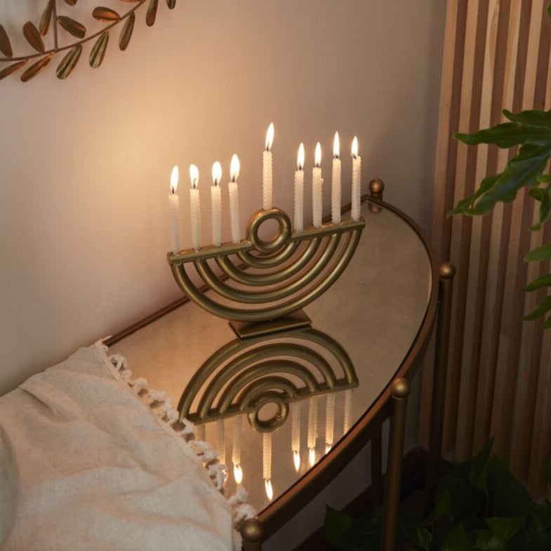 A Golda Menorah with candles on a table.