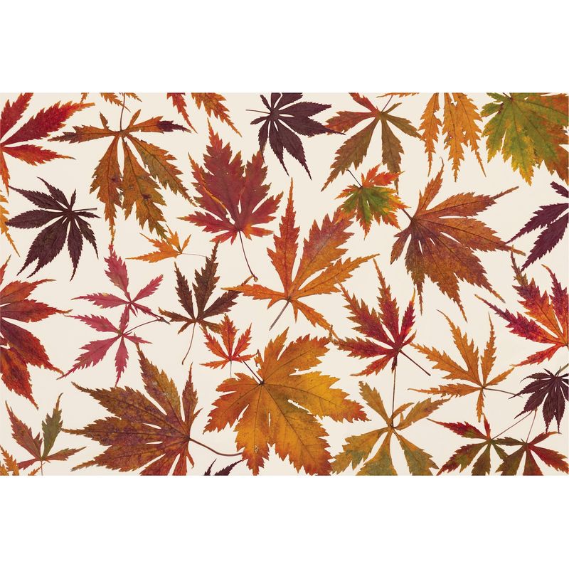 A cream Hester &amp; Cook paper placemat covered in a spray of fall maple leaves in vivid reds, oranges and yellows. 